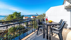 A balcony with a table and chairs, overlooking a coastal view. - Apartments Brodarica Beach (Sibenik)