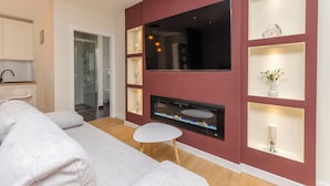 A modern living room with a flat-screen TV, built-in fireplace, and decorative shelves. - Apartment Oldtown With Parking (Vodice)