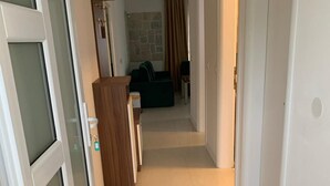 Ein schmaler Flur mit einem Holzschrank, einem kleinen Tisch und einer Couch im Hintergrund.