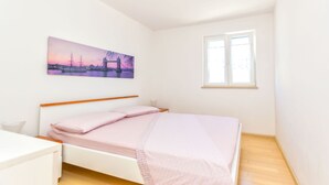 Un dormitorio con cama, escritorio, ventana y un cuadro de un puente.