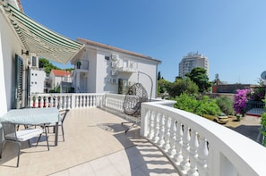 A balcony with a table and chairs, a hanging chair, and a white railing. - Apartments Big (Vodice)