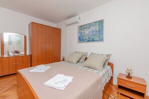 Un dormitorio con cama, armario, un cuadro y mesita de noche.