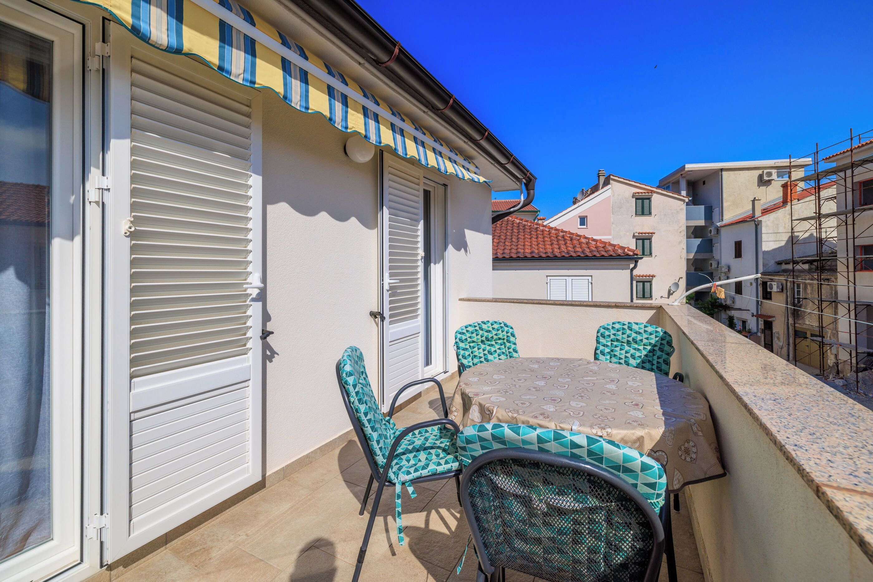 A balcony with a table and chairs, a sliding door, and a tiled floor.