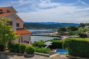 A coastal property with a swimming pool, a view of the marina, and mountains in the background. - Apartments Tariba (Rab)