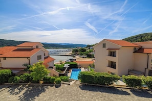 A residential area with a swimming pool, terraced houses, and a marina in the background. - Apartments Tariba (Rab)