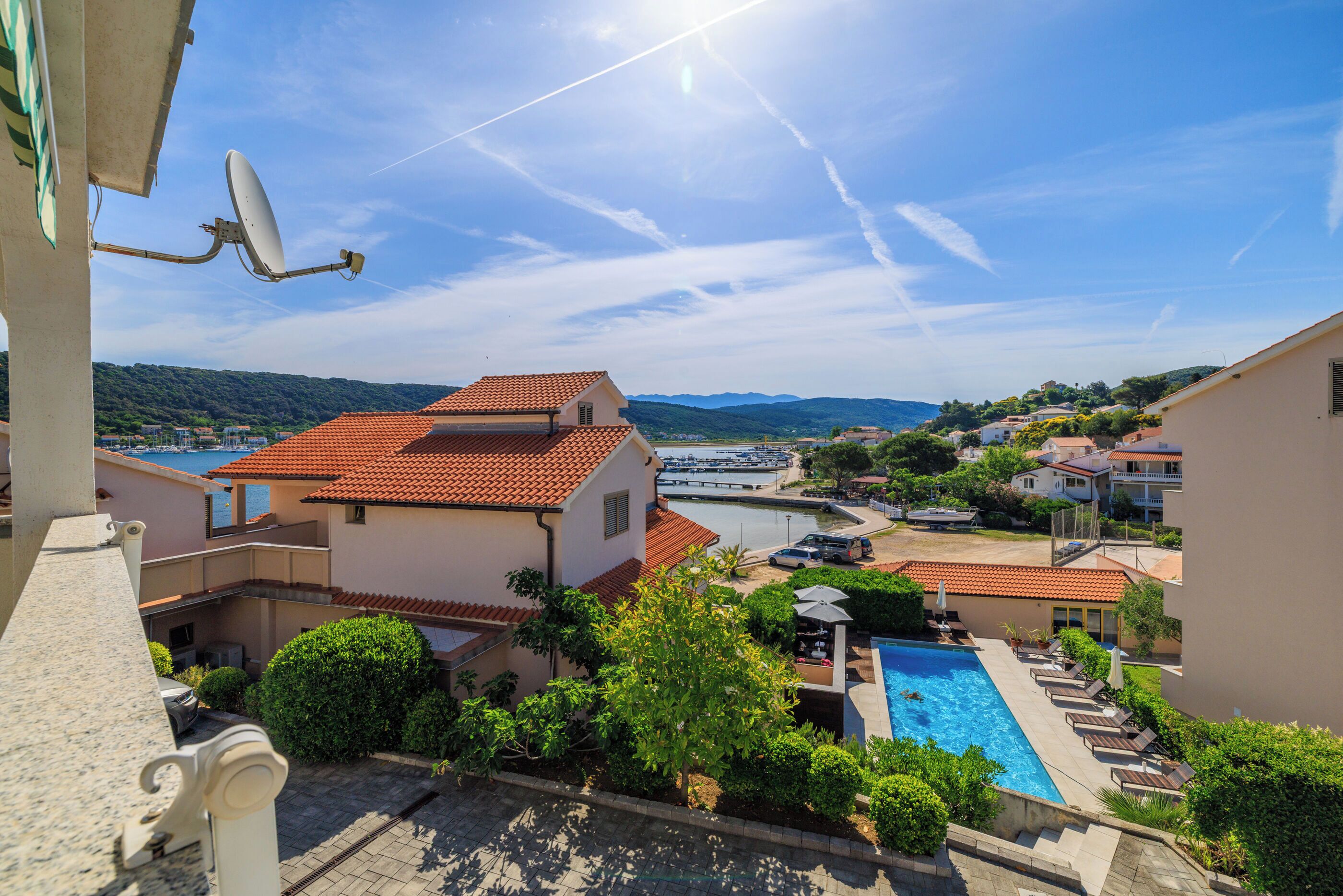 A residential area with a swimming pool, a satellite dish, and a view of a marina.