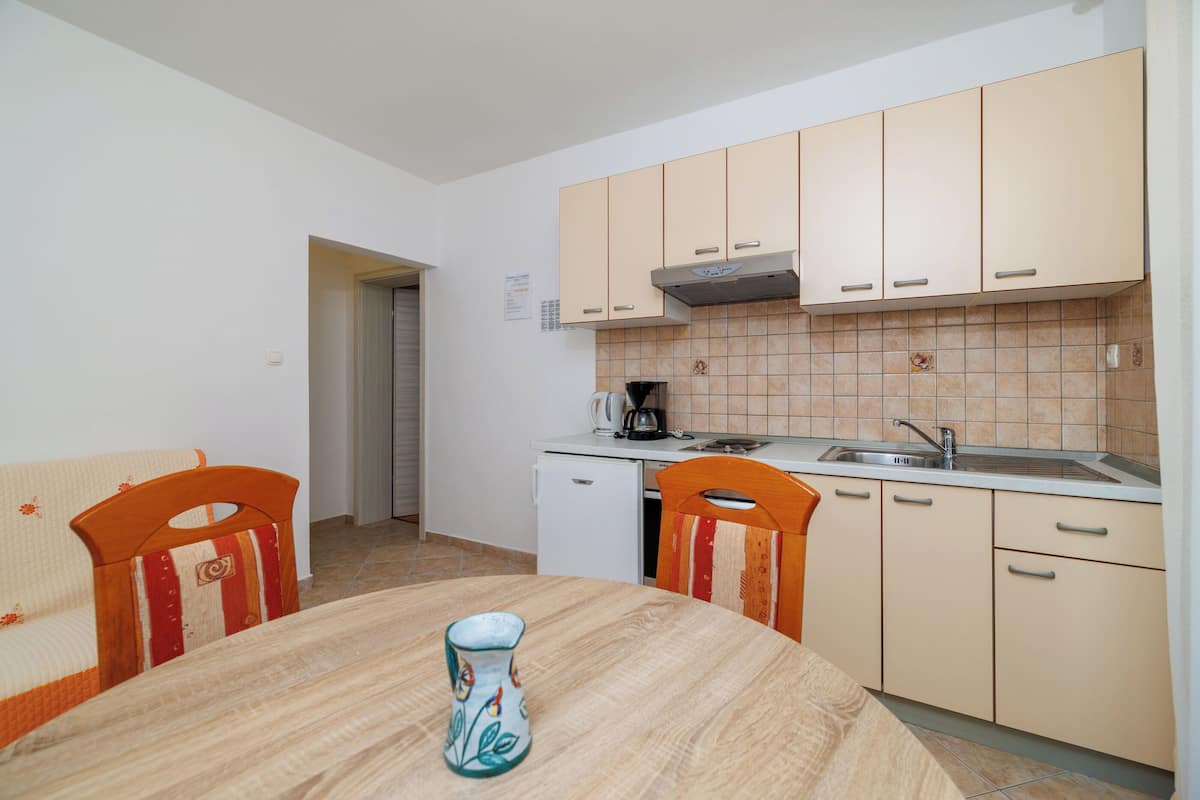 A small kitchen with a dining table, chairs, and a coffee maker.