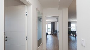 A hallway with a wooden floor leading to a dining area with chairs and a table. - Apartments Lenolu (Vodice)