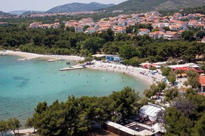 A coastal town with a beach, clear turquoise waters, and a dense cluster of red-roofed buildings. - Apartments Lenolu (Vodice)