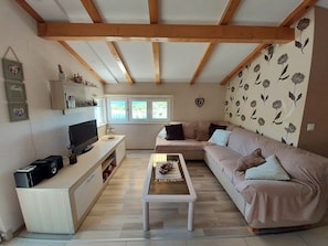 A living room with a sofa, a coffee table, a TV, and a window with a view. - Apartment D&D Grubisic (Sibenik)