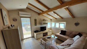A living room with a sofa, coffee table, TV, and a balcony door. - Apartment D&D Grubisic (Sibenik)
