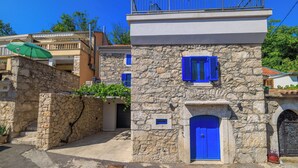A stone building with a blue door and shutters, a balcony, and a small sign. - House Maris (Vinodol)