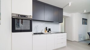 A modern kitchen with white cabinets, a black oven, and a stainless steel range hood. - House Maris (Vinodol)