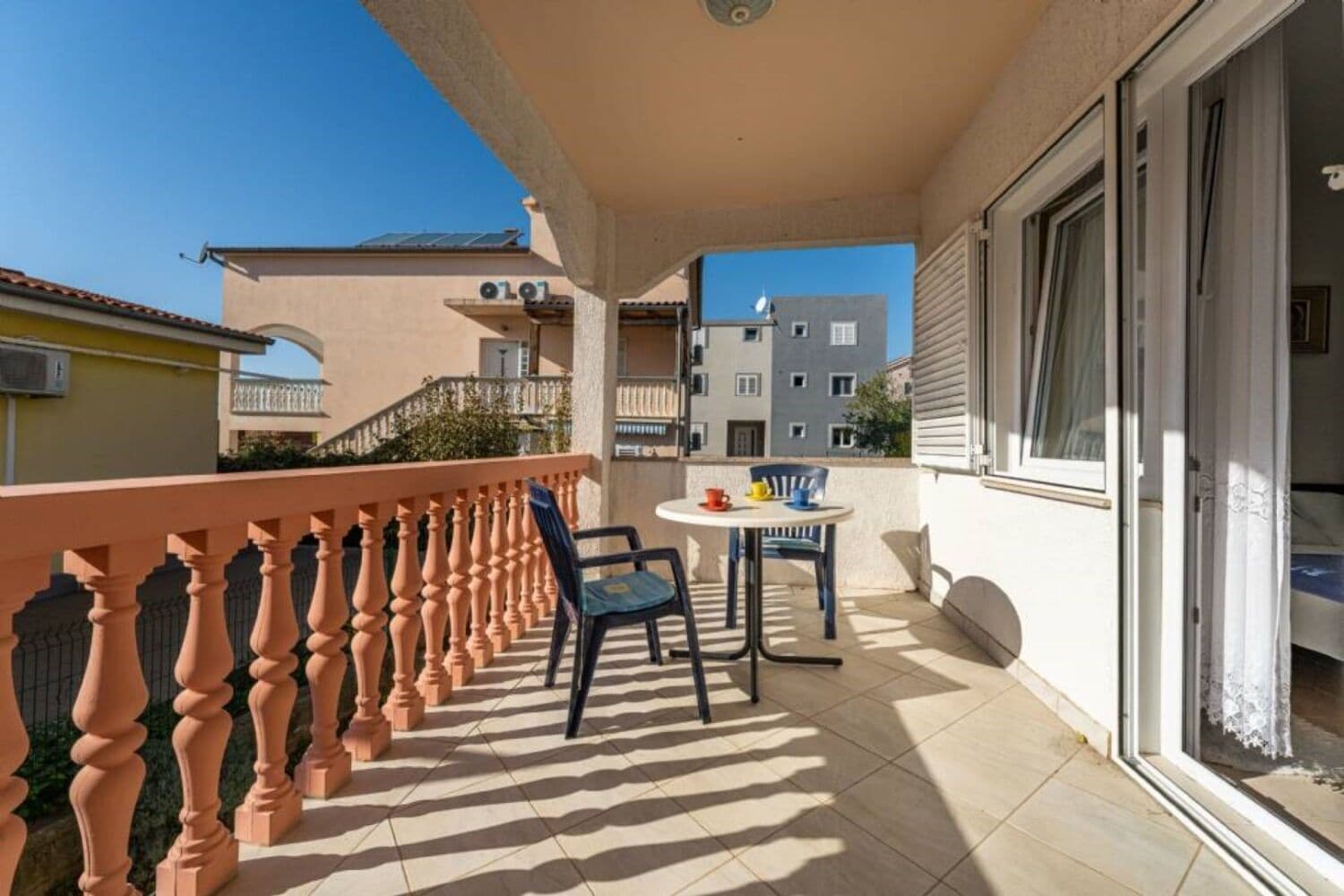 A balcony with a tiled floor, a table with chairs, and a railing.