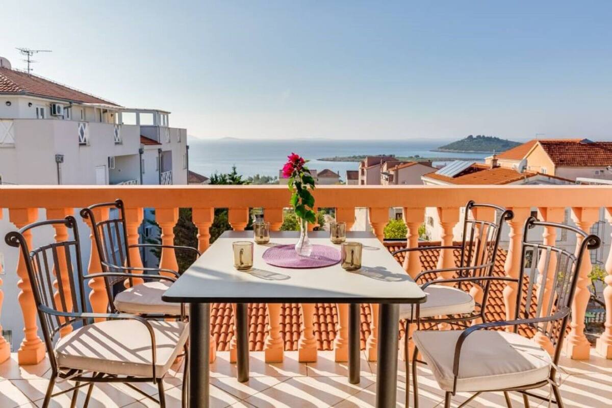 A terrace with a table and chairs, overlooking a coastal view.