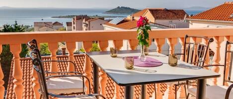 A terrace with a table set for two, overlooking a coastal view.