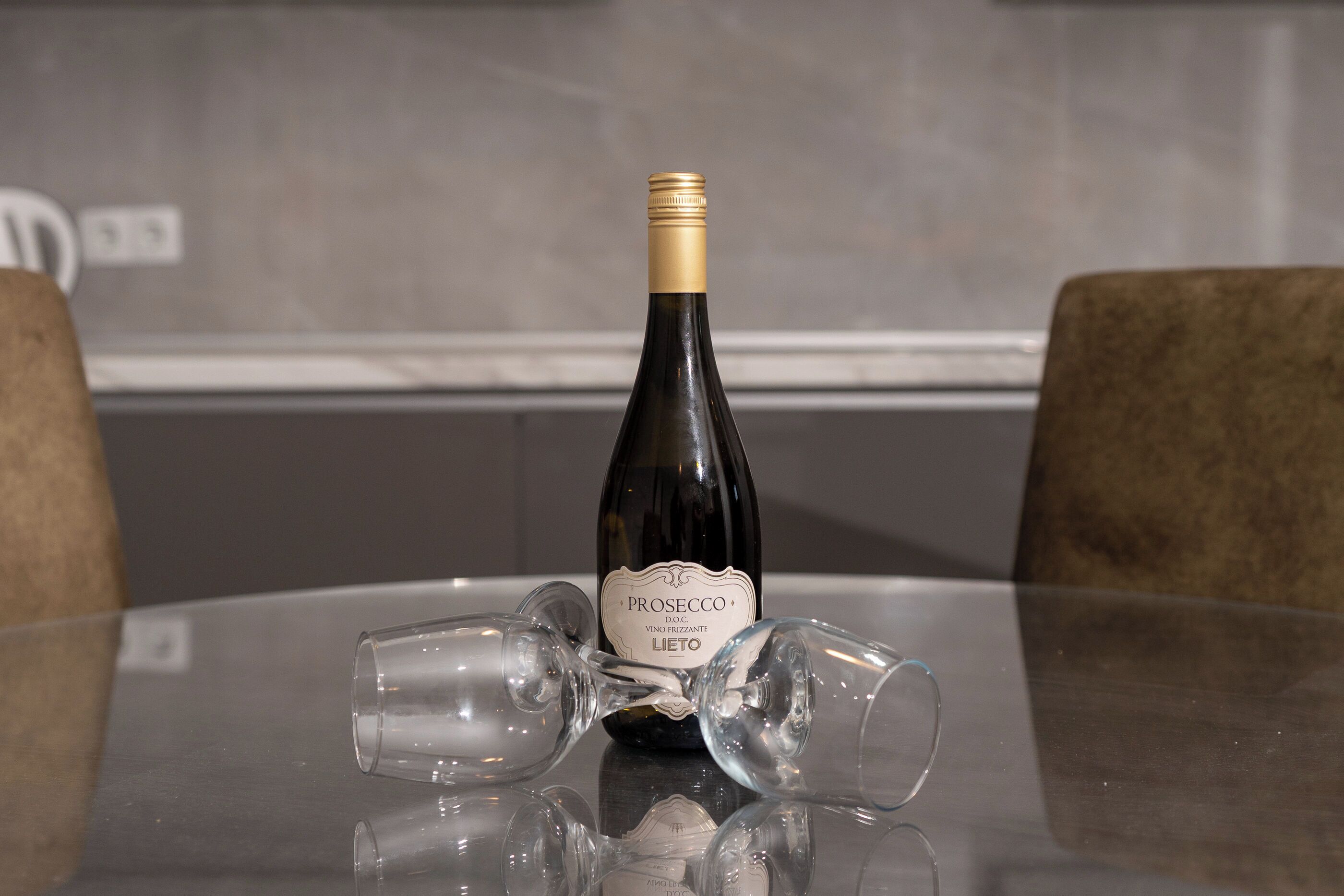 Una bottiglia di vino su un tavolo con tre bicchieri vuoti.