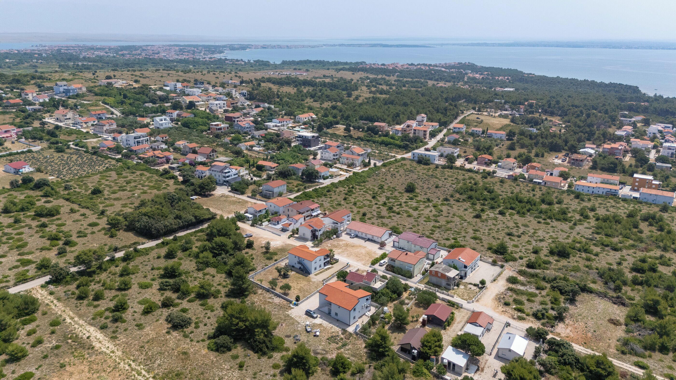 Une vue aérienne d’un quartier résidentiel, avec des maisons, des routes et une côte en arrière-plan.
