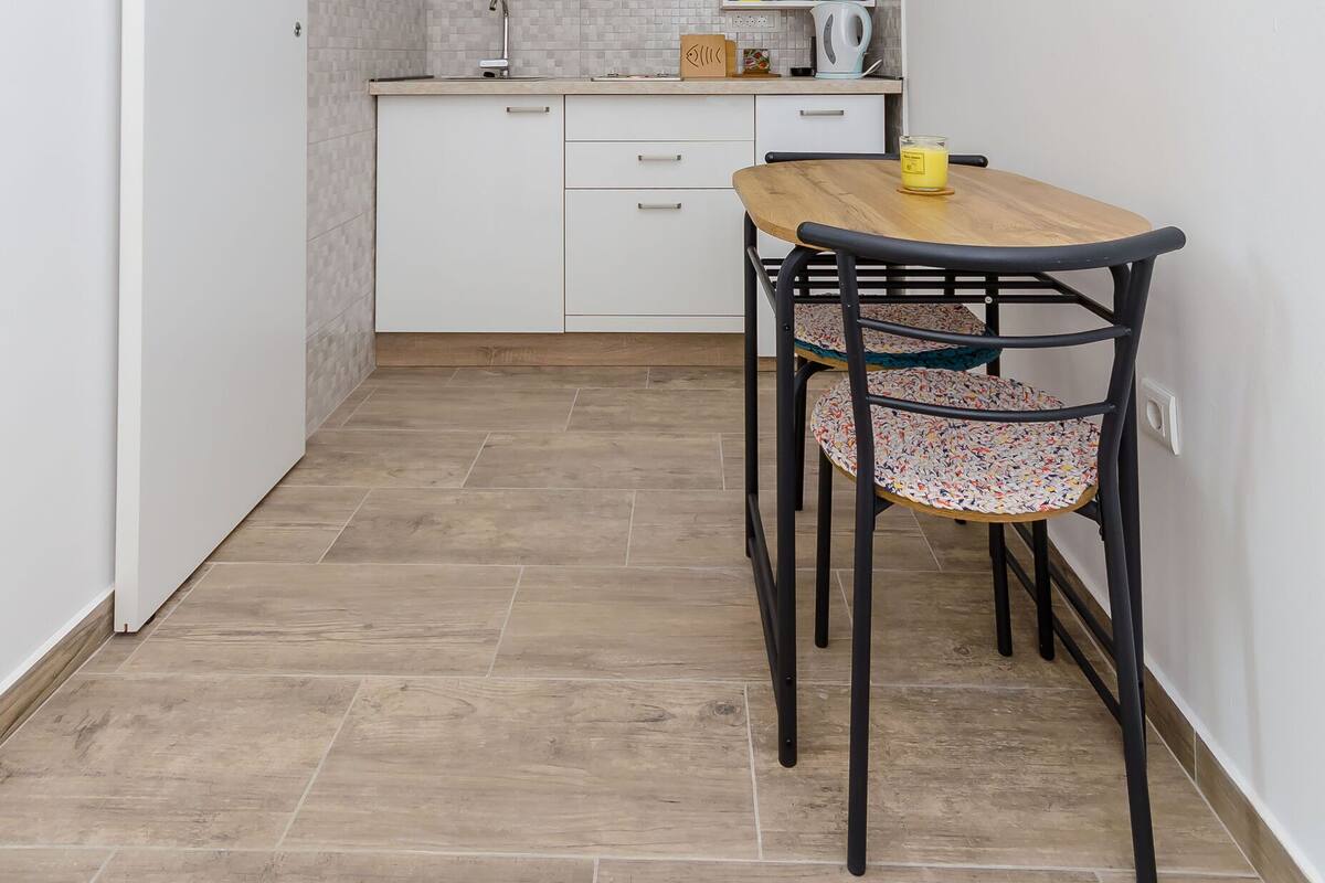 A compact kitchen with white cabinets, a wooden table, and two chairs.