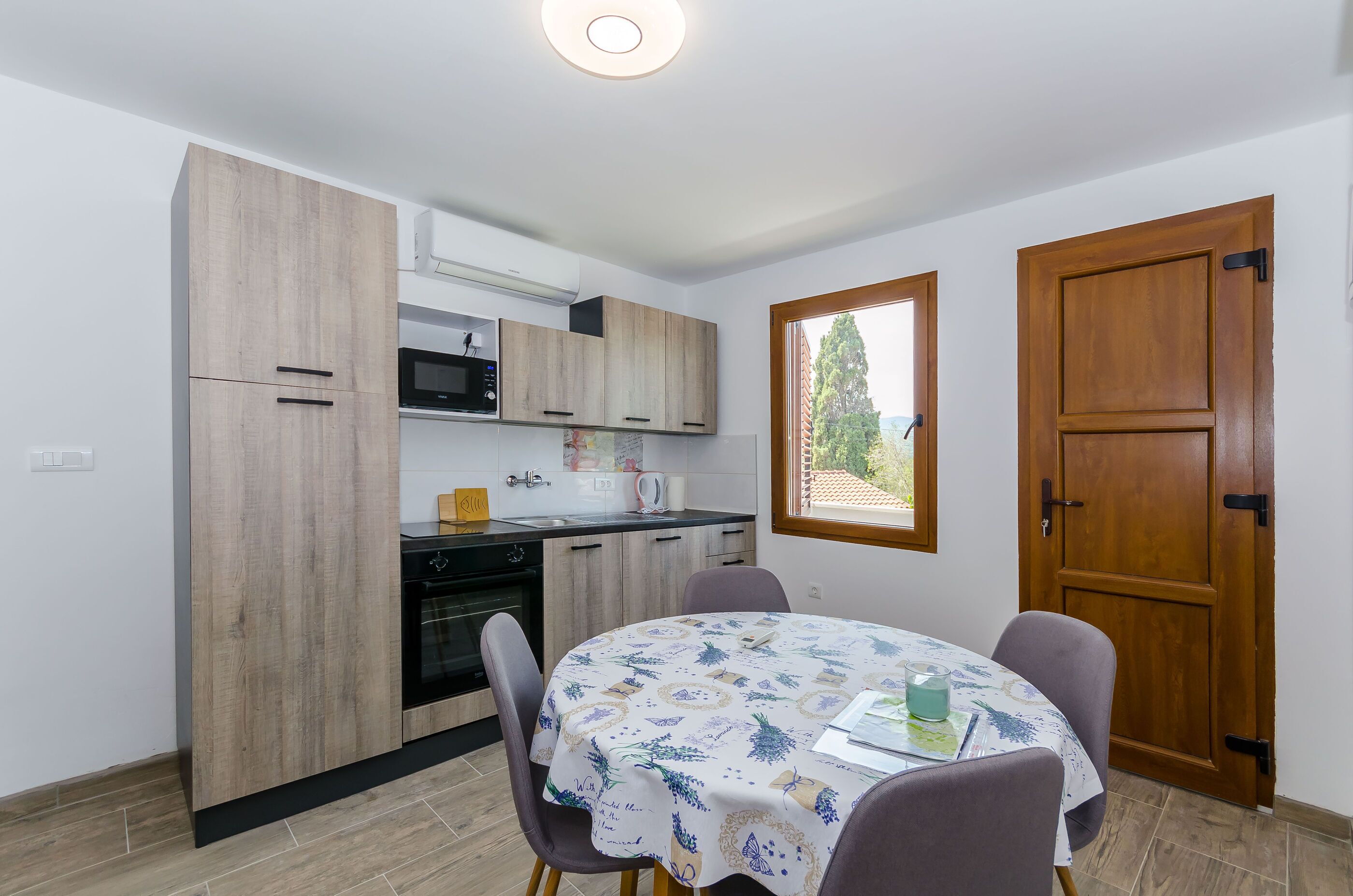 A compact kitchen with wooden cabinets, a microwave, and a dining table with chairs.