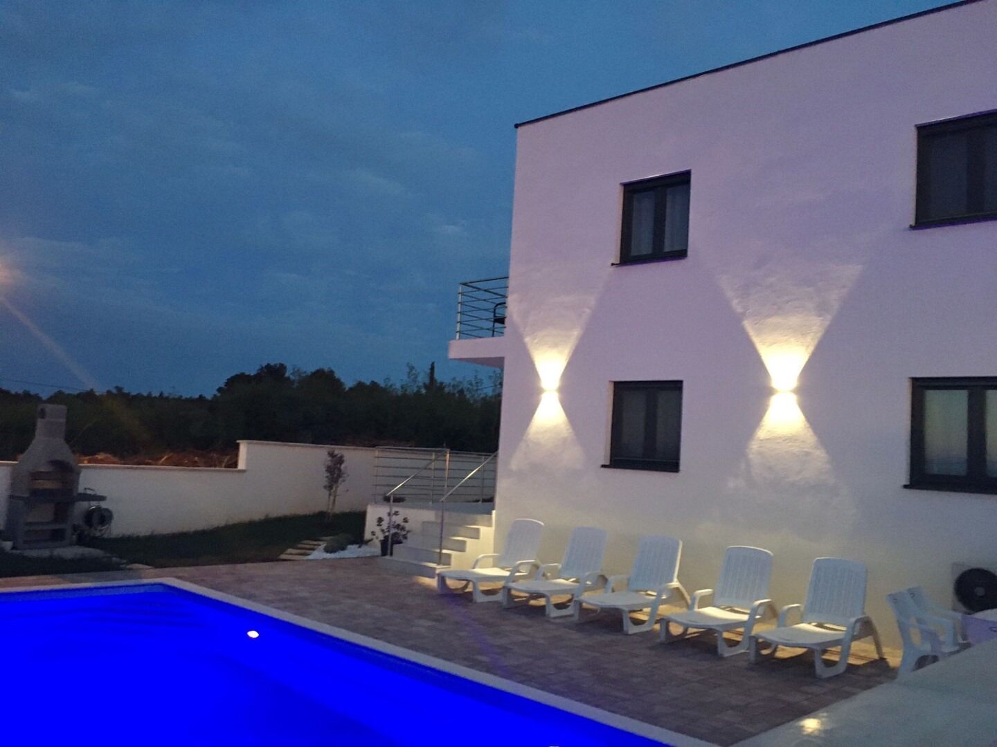 A modern building with a pool and sun loungers.
