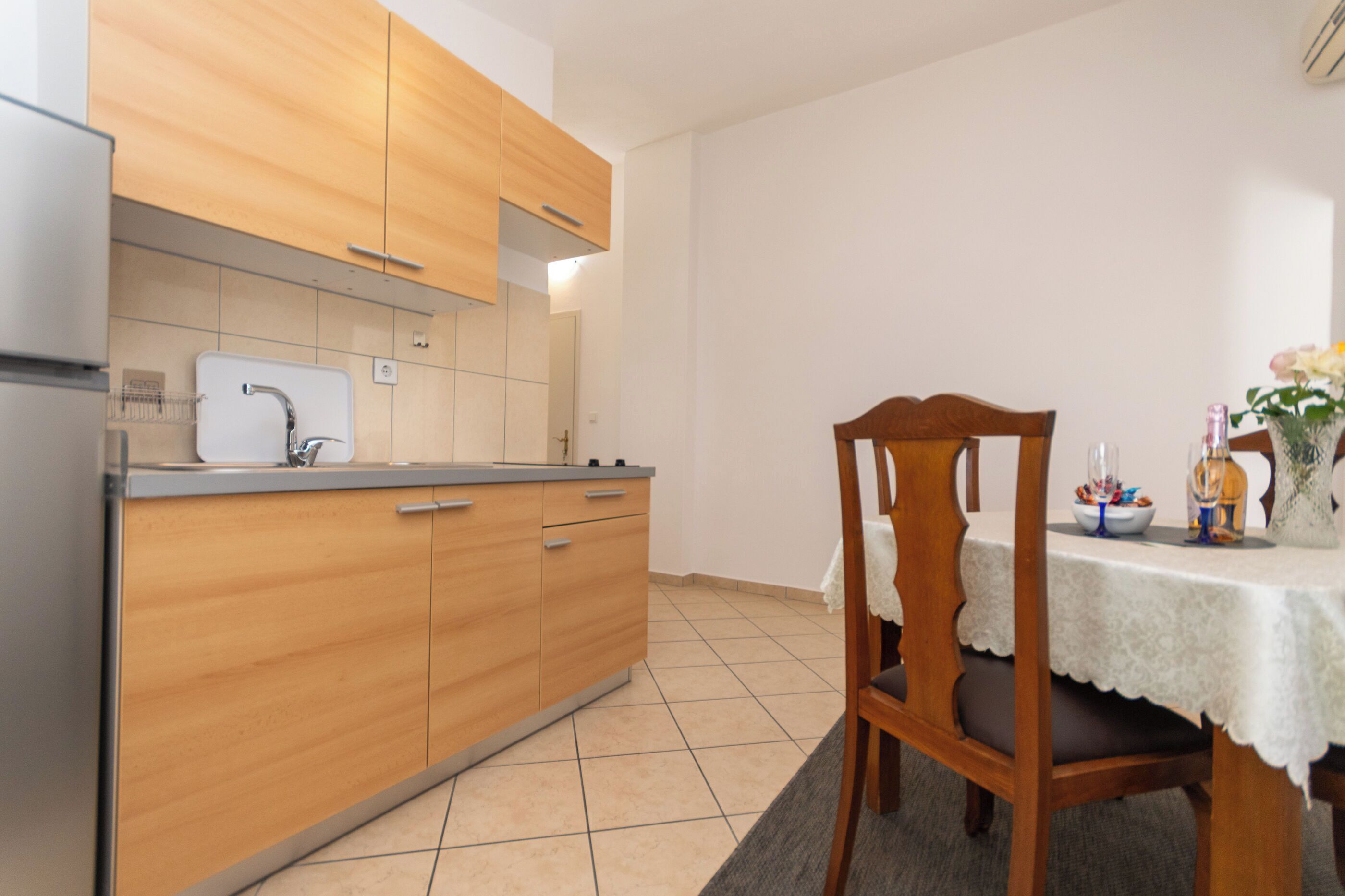 Une cuisine moderne avec des meubles en bois, un évier encastré et un coin repas comprenant une table et des chaises.