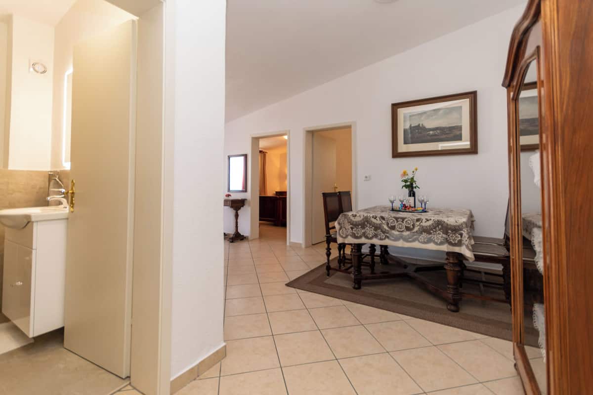 A dining area with a table set for two, a mirror, and a framed picture on the wall.