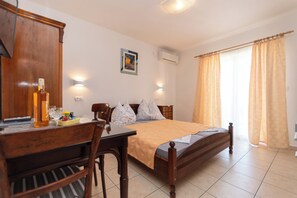 A bedroom with a wooden bed, a desk with a chair, a lamp, and a picture on the wall. - Apartments Antique Ivo (Vodice)