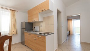 Eine moderne Küche mit Holzausbau, einem Einbauofen und einem Spülbecken. Es gibt einen Essbereich mit einem Stuhl und einem Tisch.