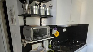 Een compacte keuken met een ingebouwde toasteroven, een spoelbak en een zwart aanrecht.