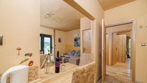A cozy room with a wooden dining table, a sofa, and a view of the outdoors. - Apartment Vesna (Rab)