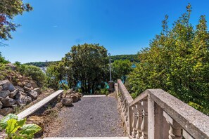 A stone staircase leading to a viewing platform with a clear view of a lake and surrounding trees. - Apartment Vidas (Rab)