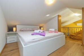 Una camera da letto con un letto grande, lampade ai comodini, una panca di legno e una parete gialla.