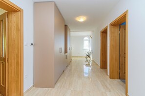 Un corridoio con porte in legno, pavimento piastrellato e una luce a soffitto.