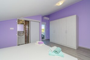 A bedroom with a bed, a wardrobe, a bathroom with a sink, and a shower area. - Apartment Vidas (Rab)