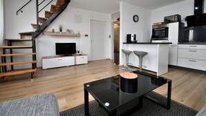 A modern apartment with a staircase, a kitchen with a microwave, and a dining area with two bar stools. - Apartment Bellevue (Vodnjan)