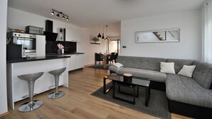 A modern kitchen with a central island, a dining area with a table and chairs, and a living area with a sofa and a coffee table. - Apartment Bellevue (Vodnjan)