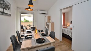 A dining area with a wooden table set for four, black chairs, and pendant lighting. - Apartment Bellevue (Vodnjan)