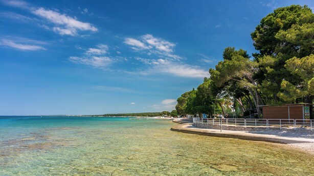 A clear beach with a sandy shore and a pier extending into the water. - Apartment Bellevue (Vodnjan)