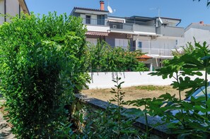 A residential building with balconies, a satellite dish, and a white wall in the foreground. - Apartments Beachfront Srima (Vodice)