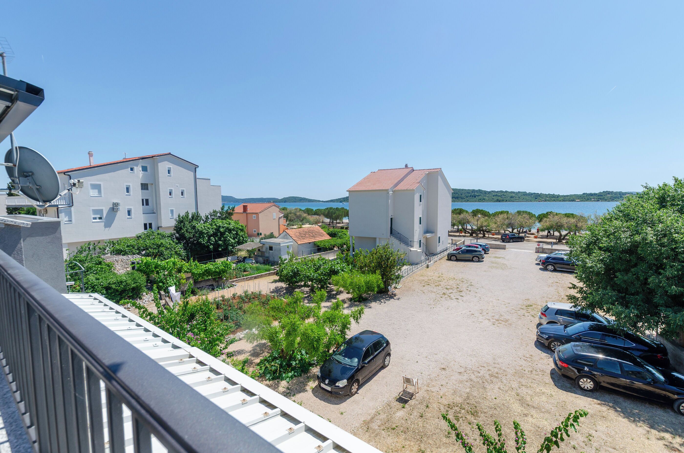 A residential area with buildings, a parking lot, and a view of the sea.