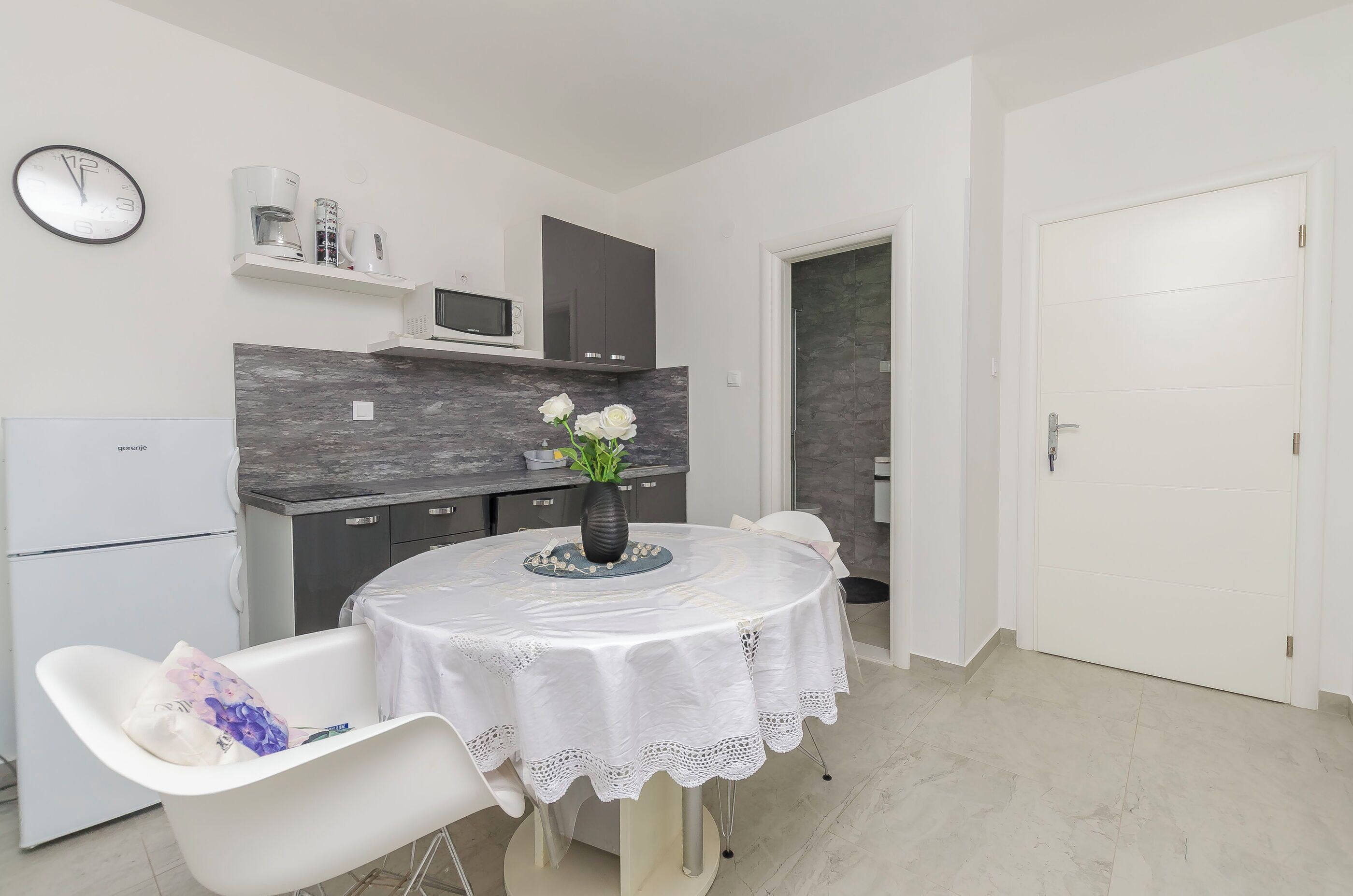 A modern kitchen with a microwave, cabinets, and a clock on the wall.