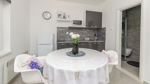 Eine kleine Küche mit Mikrowelle, Kaffeemaschine und einer Uhr an der Wand.