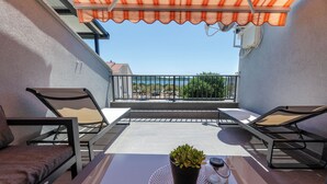 Ein Balkon mit zwei Stühlen, einem Tisch, einem Blumentopf und Blick aufs Meer.