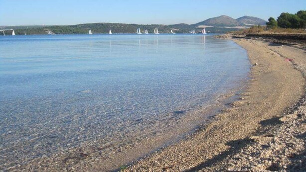 Una spiaggia di ciottoli con mare calmo.