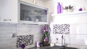 Una cucina moderna con lavello in acciaio inossidabile, forno a microonde e pensile in vetro sopra il bancone.