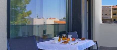 A balcony with a table set for two, large windows, and a view of buildings.