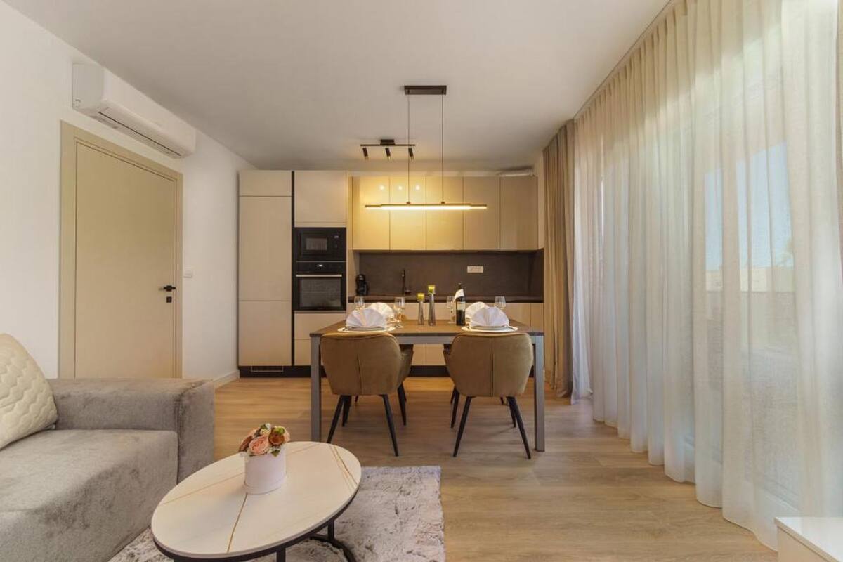 A modern living room with a sofa, a coffee table, and a dining area with chairs and a table set for two.