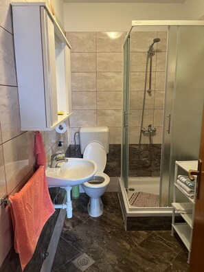 A bathroom with a toilet, sink, and glass-enclosed shower. - Apartments Zora (Biograd na Moru)