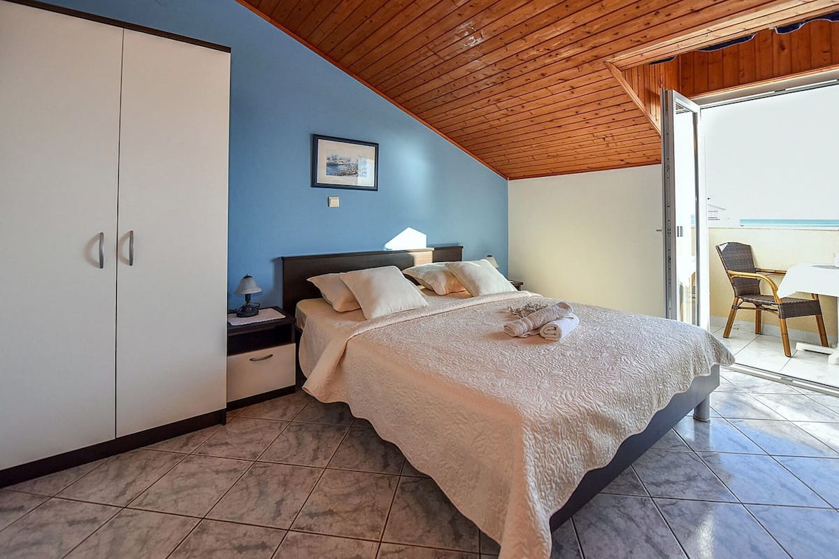 A bedroom with a bed, nightstand, and a view of the outside.